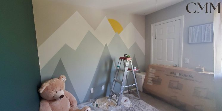 Painter’s tape being removed to reveal sharp lines in a geometric nursery mural.